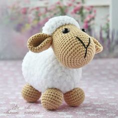 a crocheted sheep sitting on top of a pink tablecloth with the words secidathoe omicame written above it