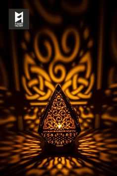 an intricately designed candle holder is lit by the light from behind it on a dark background