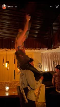 two people are dancing in the middle of a room with lights and curtains on the ceiling