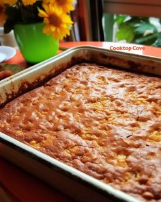 a casserole dish sitting on top of a table with yellow flowers in the background