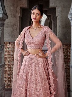 Editor's Note Dusty Coral Tulle Lehenga Choli Set With A Beautiful Floral Jaal Set In Tonal Sequins, Beads, And Crystals Color: Dusty Coral Fabric: Tulle Care: Dry Clean Only About the Designer Nitika Gujral’s journey with designing clothes started almost four decades back while she was still in high school and held her first exhibition for family and friends. Making clothes has been a part of her life ever since. Pink Reception Lehenga, Dusty Pink Lehenga, Coral Lehenga, India Traditional Dress, Lehenga Ideas, Indian Fits, Lehenga Top, Sleeveless Blouse Designs