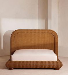 a bed made out of wicker with white sheets and pillows on the bottom side