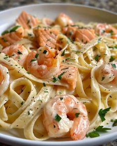 pasta with shrimp and parmesan cheese in a white bowl on a marble table