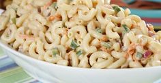 a white bowl filled with macaroni salad on top of a striped table cloth