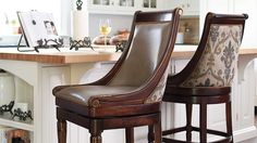 two brown leather bar stools sitting on top of a kitchen counter