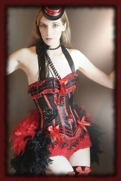 a woman wearing a red and black corset with feathers on her skirt,