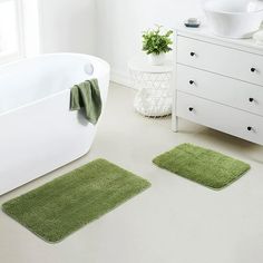 two bath mats sitting next to each other on the floor in front of a tub