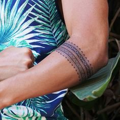 a woman with a tattoo on her arm holding onto a banana leaf and looking at the camera