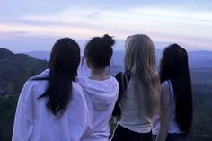 four girls standing on top of a hill looking at the sky