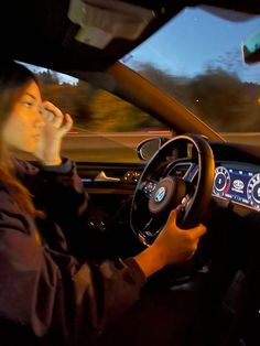 a man driving a car at night talking on the phone and holding his headphones to his ear