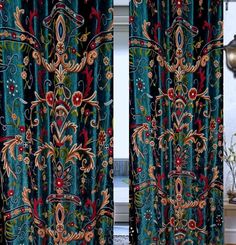 the curtains are decorated with colorful flowers and scrolls on blue velvet, which is hanging in front of a window