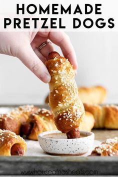 a person dipping something into a bowl with hot dogs in it and the text overlay reads homemade pretzel dogs