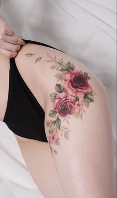 a woman laying on top of a bed wearing a black bra and floral tattoo design