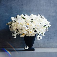 a black vase filled with white flowers sitting on top of a counter next to a rainbow