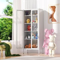 a white bookcase filled with lots of stuffed animals next to a chair and window