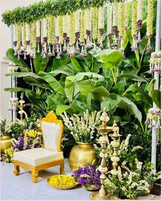 a chair sitting in front of a lush green plant filled with purple and yellow flowers