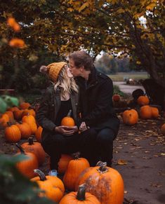 a man and woman kissing in front of pumpkins