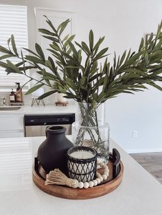 there is a vase with some plants in it on the counter next to a candle holder