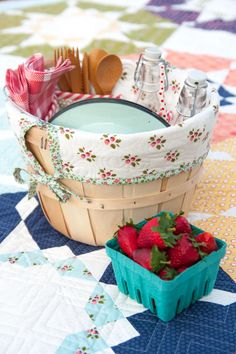 strawberries in a basket on a quilted tablecloth with utensils and spoons