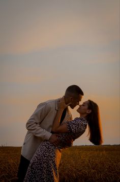 a man and woman kissing in the middle of a wheat field at sunset or sunrise