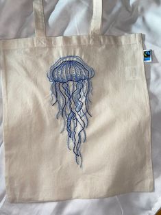 a white bag with a blue jellyfish embroidered on it