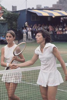 two women shaking hands over the net at a tennis match