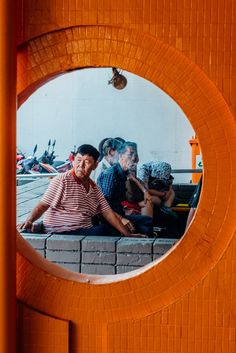 an orange door with a reflection of people sitting on the bench in front of it