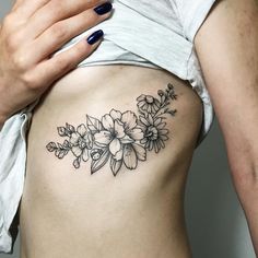 a woman's stomach with flowers tattooed on the side, and an arrow in the middle