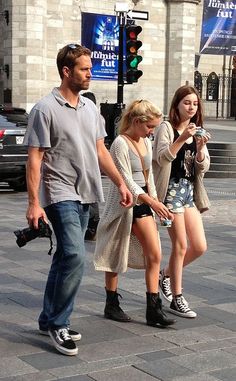 a man and woman walking down the street while looking at their cell phones in front of them