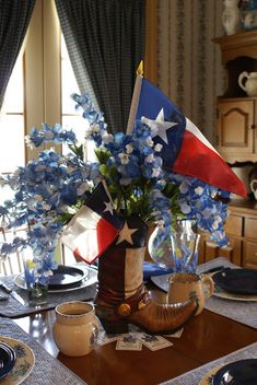 a patriotic table setting with blue and white flowers in a vase on top of the table