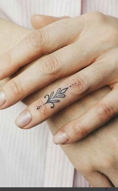 a woman's hand with an arrow tattoo on her left ring and the word love written