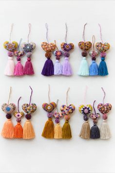 six tasselled keychais with different colors and designs hanging from the strings