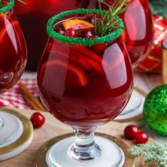 two glasses filled with red liquid and garnished with green sprinkles