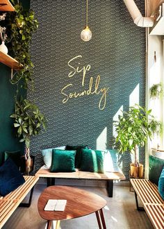 a living room with couches, tables and potted plants on the wall that says sip seriously