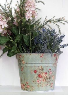 a flower pot sitting on top of a white shelf filled with flowers and greenery