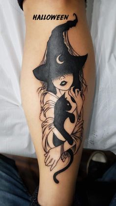 a woman's leg with a black and white tattoo design on her arm, holding a cat