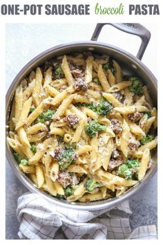 a pot filled with pasta and broccoli on top of a table next to a towel