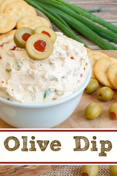 olive dip in a white bowl surrounded by crackers and vegetables