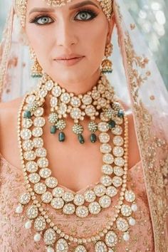 a woman in a bridal outfit with jewelry on her neck and headpieces