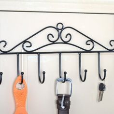 there are several pairs of scissors hanging from the hooks on the wall, and one pair is orange