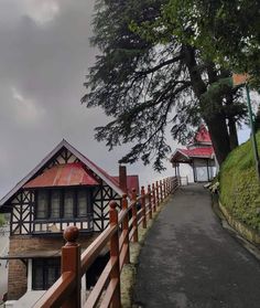 a wooden fence next to a building with a red roof and trees in the background