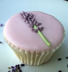 a cupcake decorated with pink frosting and purple flowers