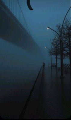 a person walking down a sidewalk in the rain at night with an umbrella over their head