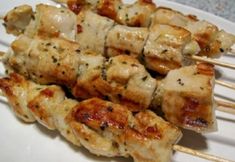 chicken skewers on a white plate covered in sauce and parmesan cheese