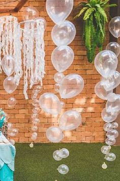 an outdoor party with balloons and streamers hanging from the side of a brick building