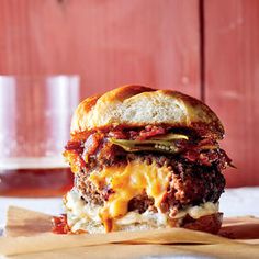 a cheeseburger is sitting on a wooden cutting board