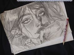 a pencil drawing of a woman's face next to a notebook with a pen on it