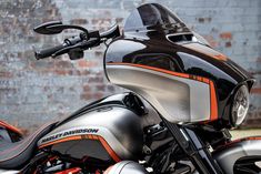 an orange and black motorcycle parked in front of a brick wall