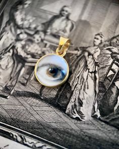 Lover's Eye pendant with an oil painting encased in gold plate over sterling with a quartz crystal cabochon which gives a magical magnifying effect, measuring 1/2" in diameter; 18" 16k gold over brass chain included. THE HISTORY: Lover's Eyes were a jewelry trend c.1785-1830 of brooches set with tiny watercolor portraits on ivory. Since they were cropped to eyes, they were in many ways more direct and intimate than traditional miniature portraits; but also because they were just eyes, they were Spiritual Gold Cabochon Necklace, Gold Spiritual Necklace With Cabochon, Spiritual Gold Necklace With Cabochon, Unique Gold Necklace For Memorial, Tiny Watercolor, Jewelry Frames, Lovers Eyes, Miniature Portraits, Historical Jewellery