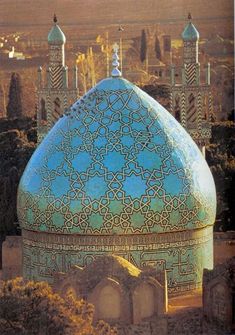 an ornate blue dome in the middle of a desert area with mountains in the background